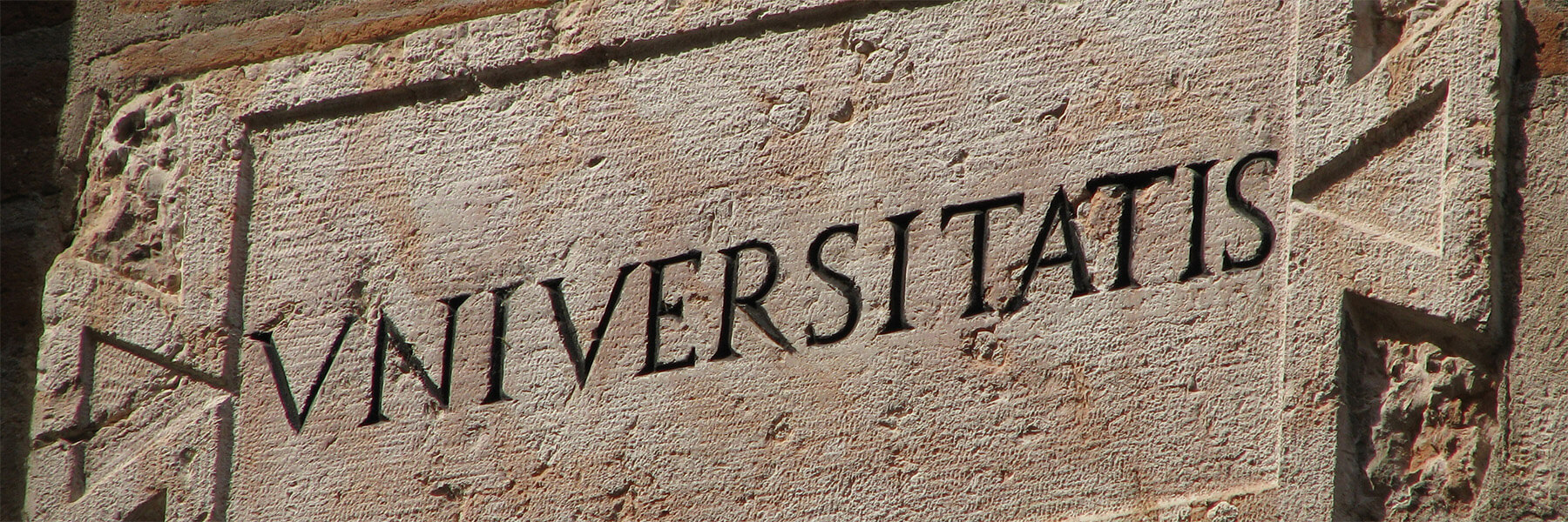 The latin word Universitatis is engraved into stone. It means University in English.