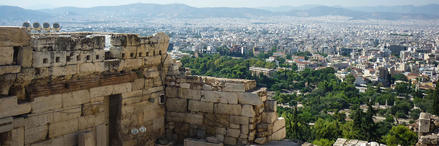 a view of a modern city in Greece with some historical structures still standing